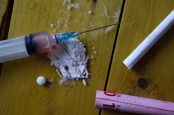 注射器、印尼盾和可在木制桌子上使用。成瘾概念
