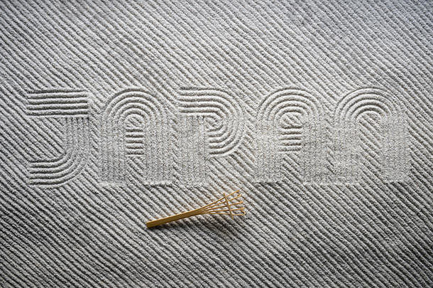 小木耙坐落在日本禅宗花园上，在纹理丰富的白沙上用大写字母耙上“日本”一词