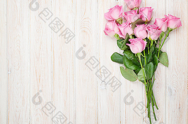 木桌上的粉红色玫瑰花束。具有空间的俯视图