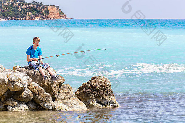 高加索人十几岁的男孩钓鱼杆海海滩
