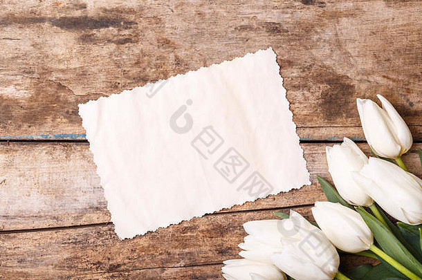 木质背景上有白色郁金香的复古纸卡。木上有花的请柬
