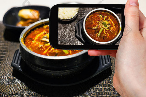 旅游概念-游客拍摄yukgaejang<strong>韩国料理</strong>（牛肉、鸡蛋、蘑菇、淀粉面、葱、蕨类、豆子、香菇辣汤）