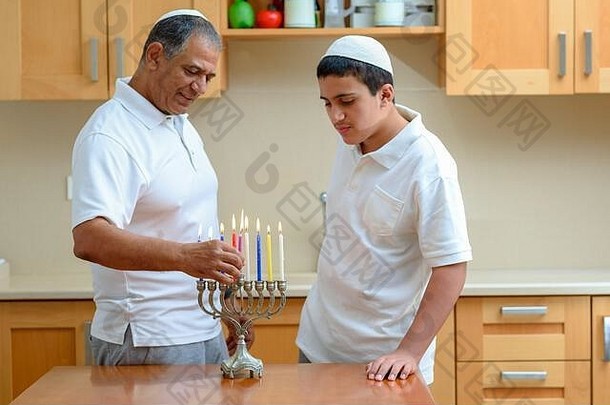 幸福家庭点燃蜡烛，共<strong>同庆</strong>祝犹太节<strong>日</strong>光明节。犹太父亲和十几岁的儿子或祖父与孙子在烛台上点燃光明节蜡烛