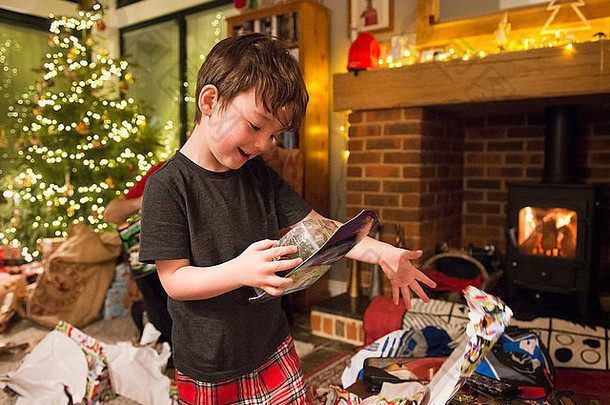 一个男孩在圣诞节打开礼物时把包装纸扔到了地板上。