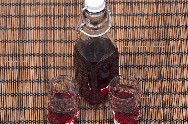 覆盆子利口酒，装在透明玻璃瓶中，带有摆动式瓶盖，并在竹垫子上放有射玻璃
