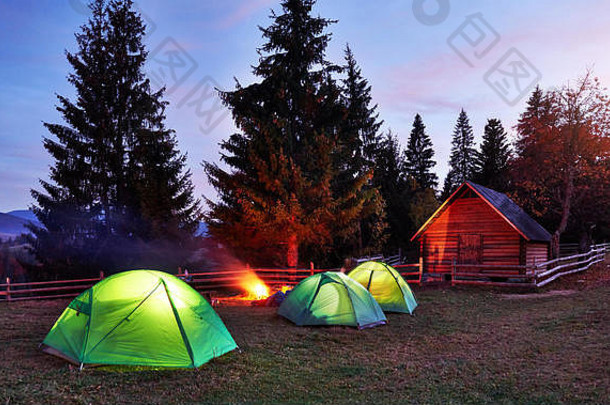 夜间露营。游客们在明亮的帐篷和木屋附近的篝火旁休息，在布满星星和银河的令人惊叹的夜空<strong>下</strong>。天体摄影