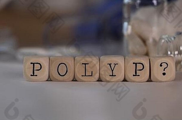 单词POLYP和问号由木制骰子组成。药丸、文件和背景中的一支笔。特写镜头