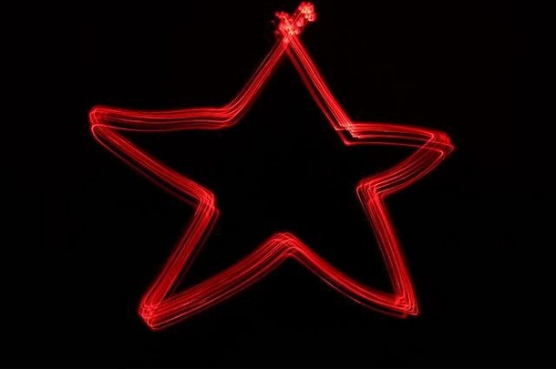 在黑色背景下，以红色霓虹灯为背景的节日圣诞形状的光绘照片。长曝光摄影。
