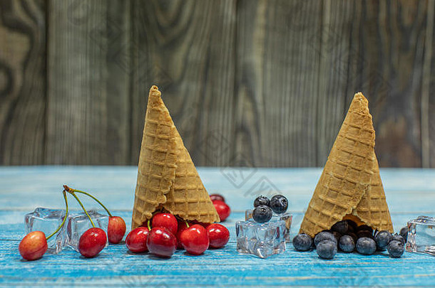 浆果冰淇淋。在木制背景上，各种新鲜蓝莓、樱桃和华夫饼蛋卷平铺在一起。夏季甜点菜单概念。冰淇淋制作