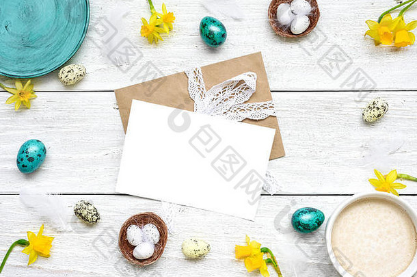 复活节贺卡的框架是鹌鹑蛋、卡布奇诺杯和白色木质背景上的春花。复活节作文。带c的俯视图