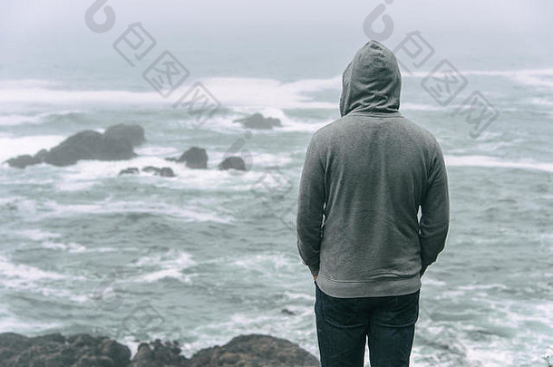 悲伤而孤独的人站在太平洋前，看着温哥华岛上暴风雨的大海。