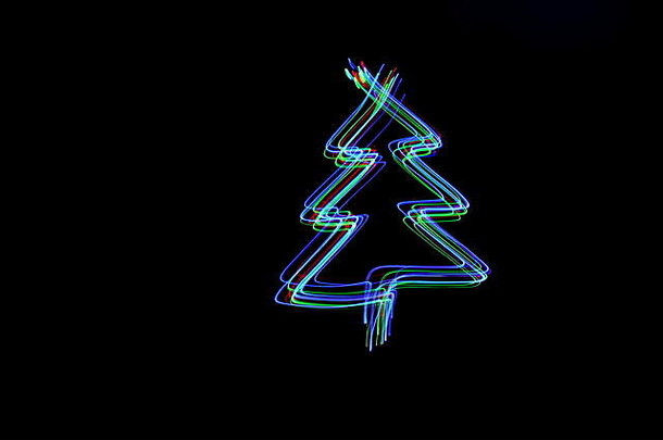 在黑色背景下用霓虹灯拍摄的圣诞树轮廓的长曝光照片。光绘摄影。
