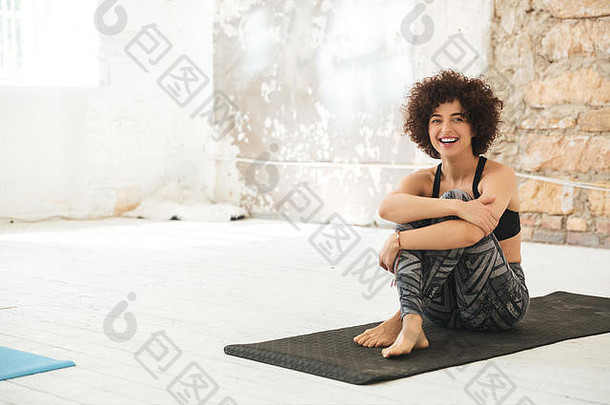 图像卷曲的快乐年轻的女人坐着<strong>瑜伽</strong>工作室