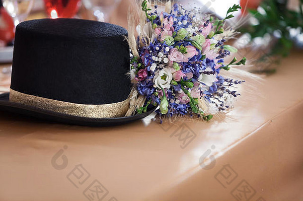 桌上有一顶复古的帽子和一束蓝色的花束。