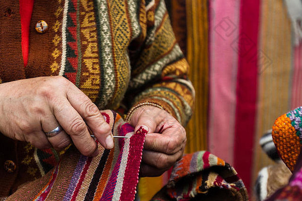 在Pisac市场上销售秘鲁纺织品的一名妇女手的特写镜头