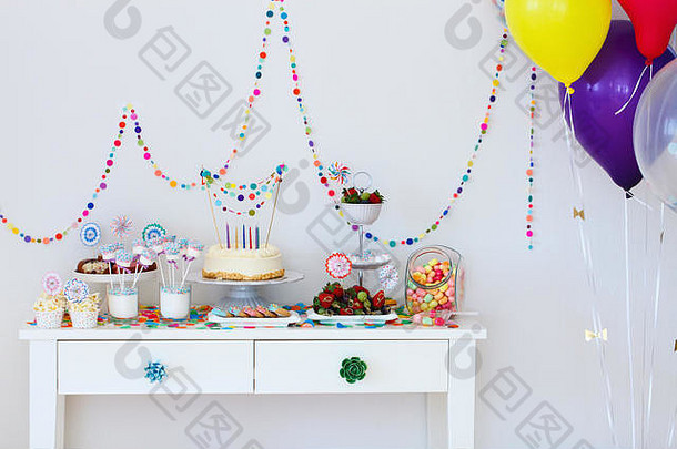 在孩子们的生日聚会上，甜点桌上摆着蛋糕、糖果、棉花糖、棒棒糖、水果和其他糖果