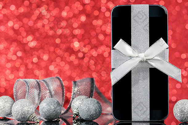 智能手机装饰圣诞节树黑色的玻璃表格红色的背景焦点智能手机