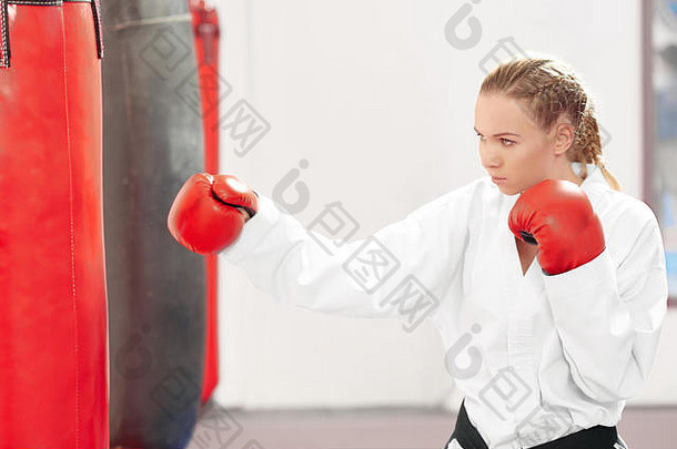 漂亮的女人打拳击重袋健身房运动空手道女孩穿和服红色的保护手套改善技术战斗硬混合武术<strong>艺术培训</strong>