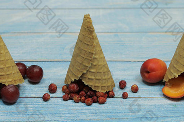 浆果和水果冰淇淋。木质背景上的华夫格蛋卷中平铺着各种新鲜水果、杏子、草莓、葡萄。夏季甜点菜单概念。冰淇淋制作