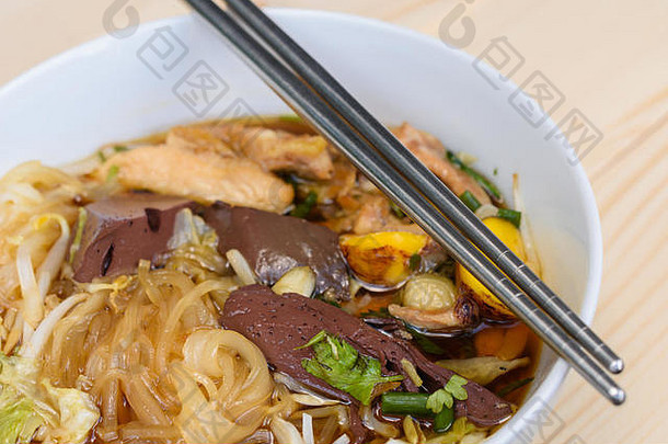 木桌上碗里的筷子汤面，泰国当地食物