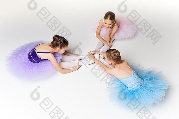 三个芭蕾舞小女孩坐在芭蕾舞裙里，一起摆姿势