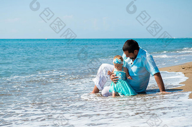 快乐的父亲和他可爱的小女儿在海滩上。