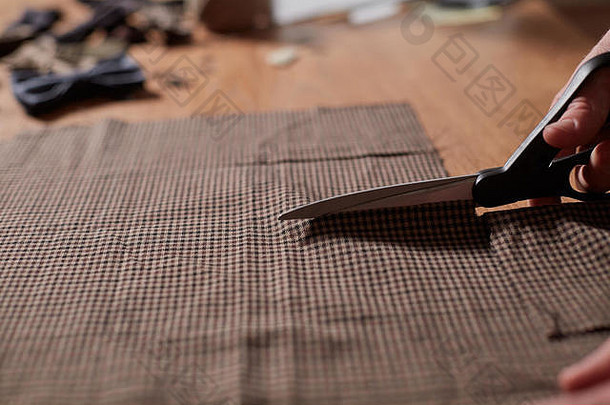 合拢裁缝的手，剪羊毛织物。这位工匠为羊毛织物的领结制作长方形坯料。在纺织厂用缝纫机工作