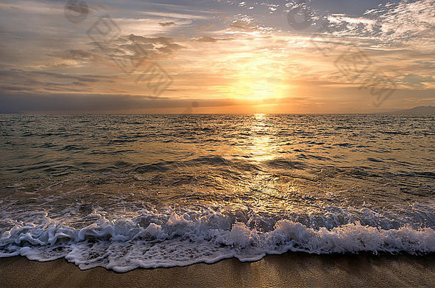 海洋日落是太阳落在海洋<strong>地</strong>平线上，<strong>轻柔</strong>的浪花沿着沙滩缓缓移动。