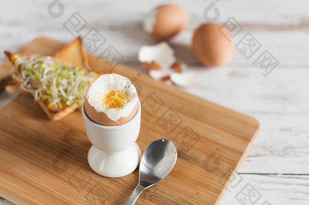 木桌上放着煮熟的鸡蛋和面包三明治，还有发芽的谷物。健康早餐的传统食物。