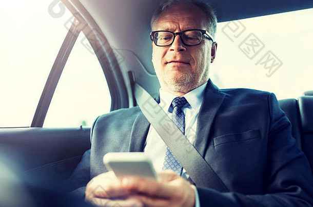 高级商人在车里用智能手机发短信