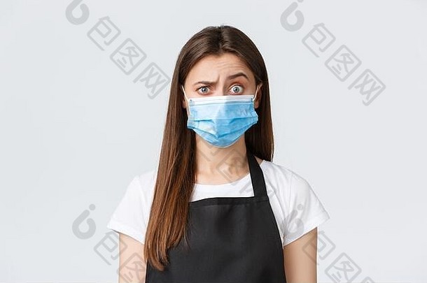 2019冠状病毒疾病，咖啡店和冠状病毒的概念。困惑和怀疑的可爱咖啡师，戴着医用面具的女售货员