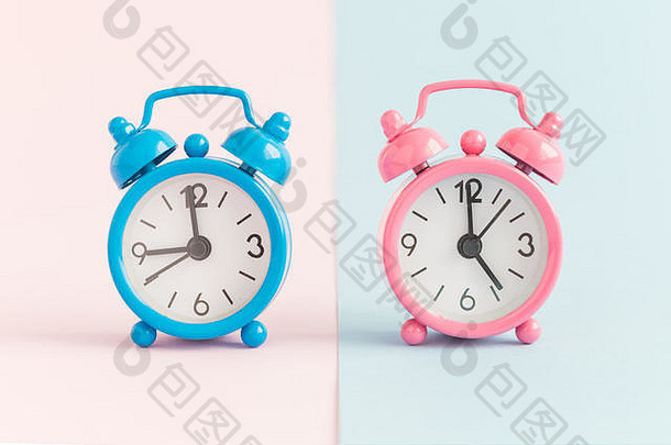 两个彩色蓝色和粉色背景的小闹钟。工作时间最小的概念。