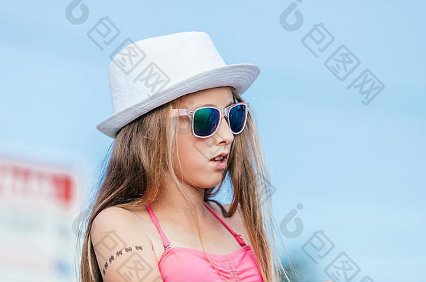 海滩上戴着帽子和太阳镜的快乐女孩的肖像。暑假