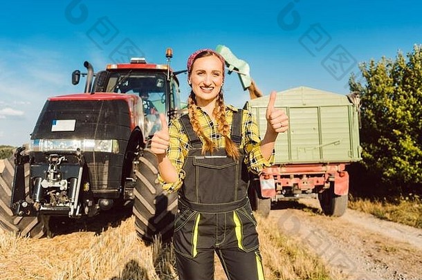 农民女人前面农业机械给竖起大拇指