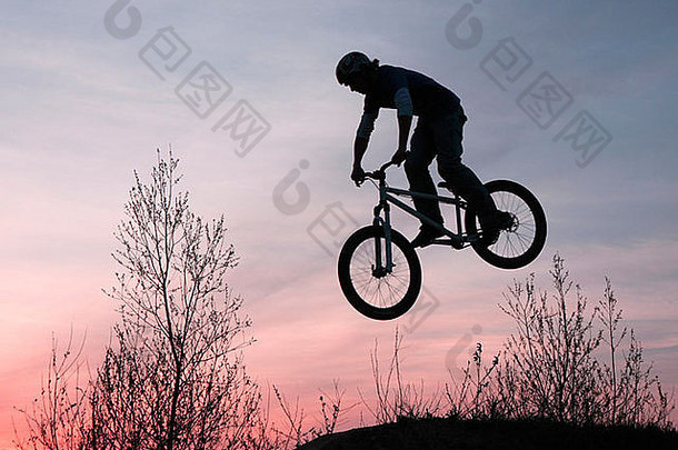 日落时，一个十几岁的男孩骑着自行车跳起来