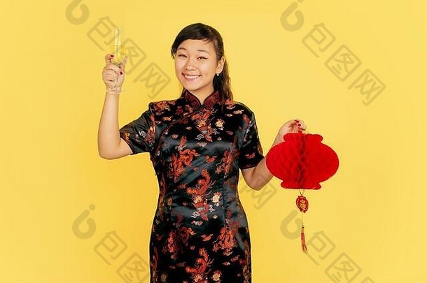 拿着香槟和灯笼。2020年中国新年快乐。黄色背景上的亚洲少女肖像。穿着传统服装的女模特看起来很开心。庆祝，情绪。空间。