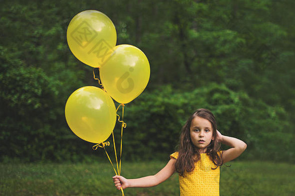 拿着黄色气球的年轻女孩