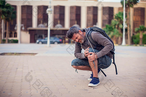 特写镜头：一名男子坐着，膝盖因室外受伤而疼痛。人、保健、医疗观念