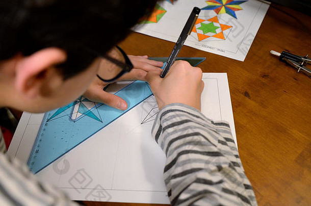 都灵，皮埃蒙特，意大利。2019年4月。一个戴眼镜的黑发白人男孩正在做技术制图作业。带指南针，尺子，正方形，它是cre