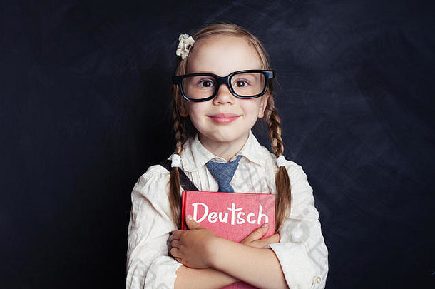在语言学校的教室里，一个带着德语书微笑的小女孩。学习德语