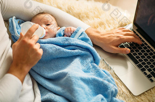 男人一边躺在床上一边用笔记本电脑喂养小宝宝