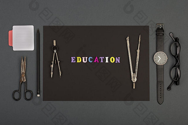 建筑教育-黑纸、木制字母的文本教育、工程工具、眼镜、剪刀、素描簿和灰色bac上的手表