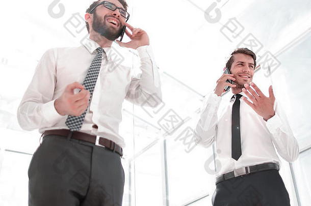 底视图。两位成功的商人在智能手机上聊天。