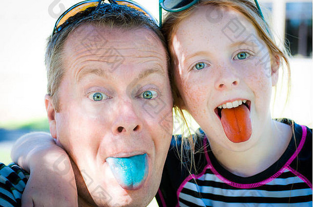 父女俩傻傻地笑着，露出糖果色的舌头。