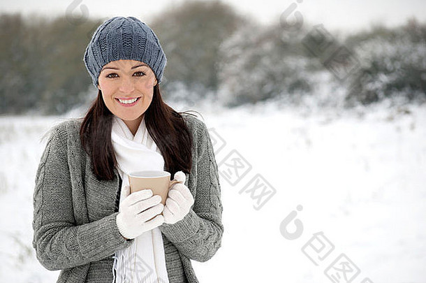 快乐的冬天女人在外面拿着杯子