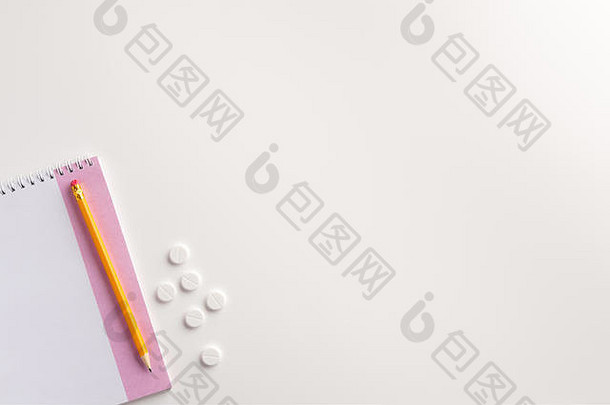 白色背景上的记事本、铅笔和药丸。医学概念。平铺。