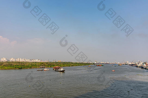 越南胡志明市——2019年3月13日：从市中心看灰蓝色的宋西贡河日落时的下游：船只、绿化带、蓝天、t