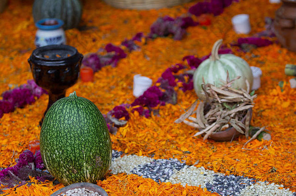 这是一个神秘的场景，墨西哥的一个祭坛上有一个南瓜，放在用万寿菊花瓣做成的地毯上
