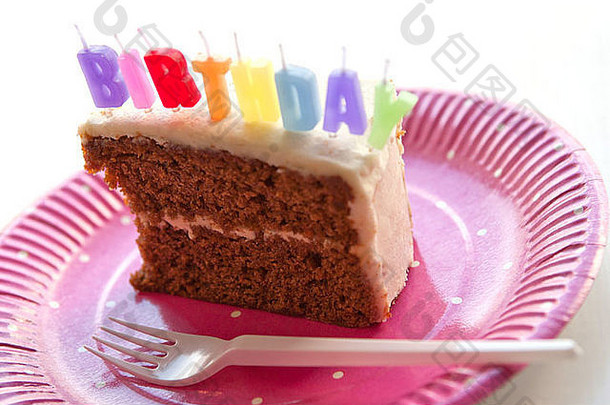 一片生日蛋糕和生日蜡烛，放在粉红色的纸盘子上