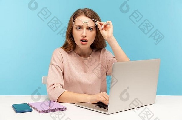 惊讶的聪明女人摘下眼镜，惊讶地张<strong>大嘴巴</strong>，在笔记本电脑上工作，表示非常惊讶，震惊。室内stu